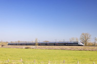 Fransa 'nın Saone et Loire kentindeki Cortevaix yakınlarındaki Bourgogne Franche Comte bölgesinde açık mavi gökyüzü altında seyahat eden yüksek hızlı Fransız treni.