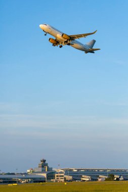 Beyaz ve sarı yolcu uçağı güneşli bir günde Prag Vaclav Havel Havalimanı 'ndan havalanıyor.