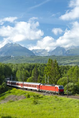 Slovakya 'nın Strba kentindeki yolcu trenini çeken kırmızı elektrikli lokomotif. Güzel bir yaz gününde arka planda High Tatras Dağları var.