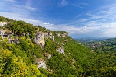 Autoire, Lot, Occitanie, Fransa 'da küçük bir köyü olan yeşil bir vadiye bakan kireçtaşı uçurumlarının nefes kesici manzarası.