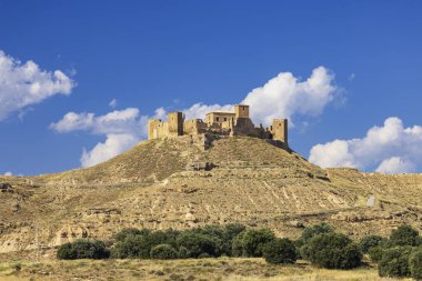 Castillo de Montearagon 'un parlak mavi gökyüzünün altında bulutların altında durduğu manzarası.