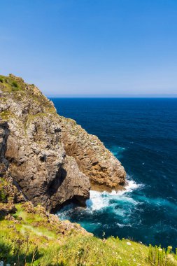 Engebeli uçurumlar Cantabria, İspanya 'da berrak mavi bir gökyüzünün altında canlı okyanusla buluşuyor.