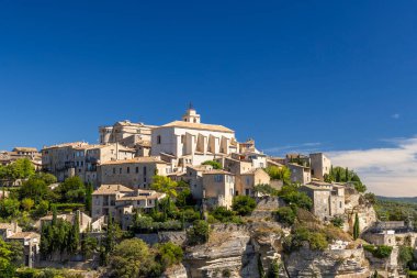 Gordes 'un tarihi tepe köyü berrak mavi gökyüzünün altında büyüleyici taş binalar.