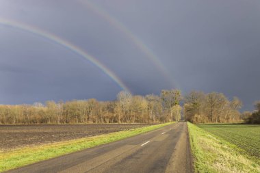 Canlı bir çift gökkuşağının altında sessiz bir köy yolu