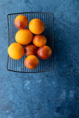 Canlı limonlar ve şeftaliler mavi arka planda bir tel askıda dizilmiş.