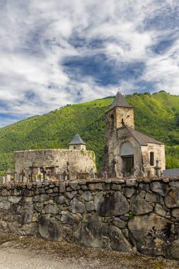Ustou, Ariege, Fransa 'da bulutlu gökyüzünün altında taş duvarlı eski bir kilise ve mezarlık.