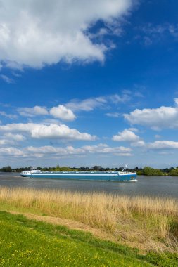 Hollanda, Lopik 'teki Lek Nehri' nde güneşli bir günde güzel bulutlarla denize açılan mavi mavna.