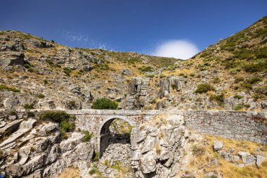 Villarejo del Valle dağlarında, Avila, İspanya 'da mavi gökyüzünün altında eski bir taş köprü.