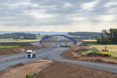 Çek Cumhuriyeti 'nde Knezeves yakınlarında bulutlu bir gökyüzünün altında, tamamlanmamış bir köprüde giden bir kamyon.