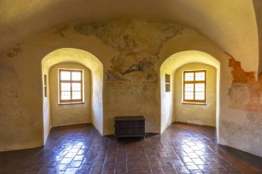 Çek Cumhuriyeti 'nin Svihov su kalesinde kemerli camları ve yıpranmış freskleri olan bir odada eski ahşap bir sandık.