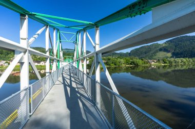 Slovakya 'nın Strecno kentinde Vah nehri boyunca uzanan metal yaya köprüsünde yeşil ve beyaz boyalı destekler ve tel örgülü korkuluklar yer alıyor.