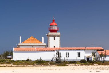 Güneşli bir günde Portekiz 'in Odemira şehrinde yer alan kırmızı ve beyaz kulesiyle Cabo Sardao Deniz Feneri' nin manzarası.