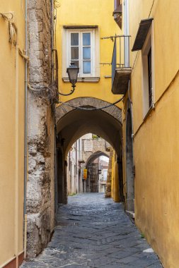 Benevento, Campania, İtalya 'nın tarihi merkezindeki sarı binaları birbirine bağlayan kemerli taş kaldırımlı sokak.