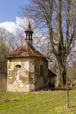 Huzurlu bir çayırda çürüyen alçı ve paslı çatısı olan küçük bir kilise.
