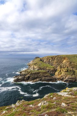 Pointe de Kastel Koz 'un Cleden Cap Sizun, Brittany' deki manzarası bulutlu bir günde dalgaların kayalıklara çarpmasıyla