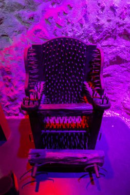 Slovenya 'nın Celje kentindeki eski şatosunda, mor ve kırmızı ışıklarla aydınlatılmış demirden işkence sandalyesi.