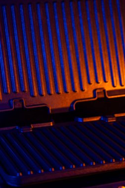 Yoğun mavi ve turuncu ışıklarla aydınlatılmış modern elektrikli ızgara dramatik bir atmosfer yaratıyor.