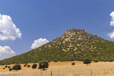 Calatrava la Nueva Şatosu Aldea del Rey 'de bir tepenin üzerinde duruyor, Ciudad Real, İspanya, mavi gökyüzünün altında beyaz bulutlarla