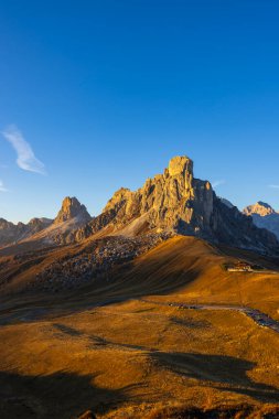 İtalyan Dolomitleri, Venedik bölgesinde Passo Giau 'nun görkemli tepelerini ve dolambaçlı yolunu aydınlatan altın saat.