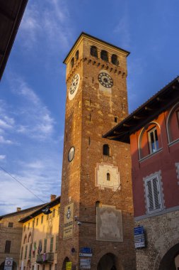 İtalya 'nın Cherasco kentindeki tarihi saat kulesi, şehrin zengin mirasının bir sembolü olan öğleden sonranın altın ışığında güneşleniyor.