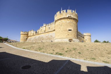 Castilla 'daki ortaçağ Grajal de Campos Kalesi ve İspanya' nın Leon kenti, açık mavi gökyüzü altında tarihi mimarisini sergiliyor.