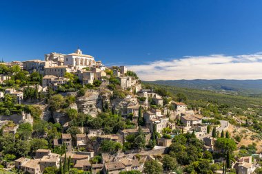 Güneşli bir yaz gününde Fransa 'nın Provence kentindeki bir köyde, uçuruma tünemiş Gordes' in resimli manzarası.