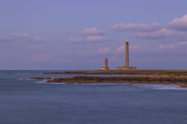 Gatteville Deniz Feneri, gün batımında kayalık sahilden Normandiya, Fransa 'da yükseliyor.