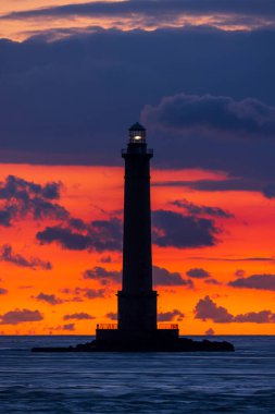 La Hague deniz feneri, Normandiya kıyılarında çarpıcı bir siluet yaratan canlı bir gün batımına karşı dimdik ayakta duruyor.