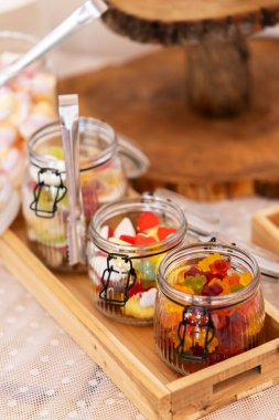 Cam kavanozlar çeşitli renkli şekerlerle, maşalarla ve ahşap tepsilerle dolu. Güzel ve şenlikli bir atmosfer yaratıyorlar.