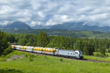 Modern elektrikli lokomotif Slovakya 'da üstü kapalı zıpzıp arabalarıyla dolu bir yük treni çekiyor