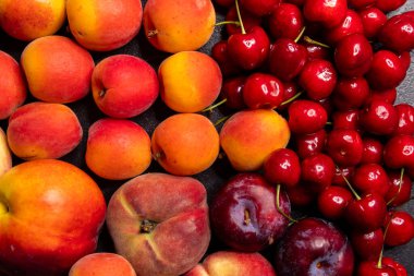 Taze yaz meyveleri, şeftaliler, kayısılar, kirazlar ve erikler de dahil olmak üzere canlı bir görüntüde olgun renkleri ve dokuları gözler önüne seriliyor.