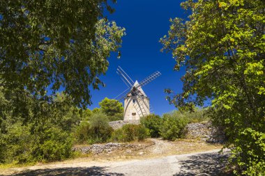 Saint Saturnin les Apt 'da resim gibi bir yel değirmeni, Fransa' nın Provence şehrinin göbeğinde yuva yapmış, sıcak bir yaz gününün güneşinde yıkanmış büyüleyici bir köy.