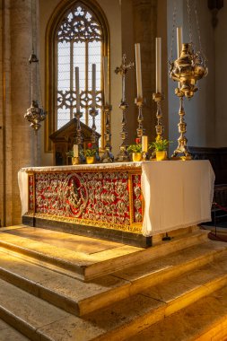 Ornate church altar displaying religious artifacts and candles with light entering through a stained glass window