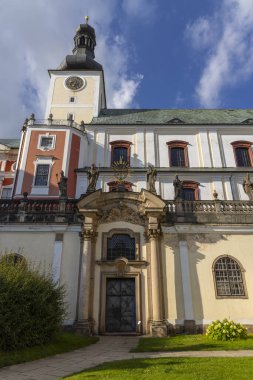 Broumov Manastırı. Karmaşık Barok detayları, bir saat kulesi ve mavi gökyüzü.