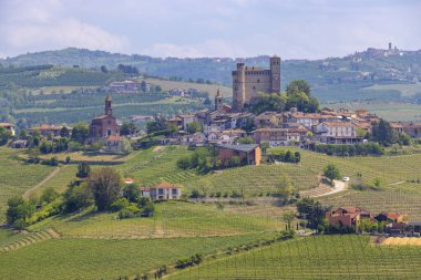 Perno köyü, bir ortaçağ şatosu ve Piedmont, İtalya 'da mavi bir gökyüzünün altındaki üzüm bağları.
