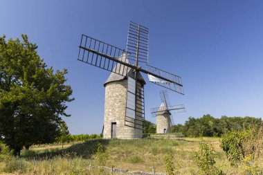 Montagne, Gironde, Fransa 'da güneşli bir tepede duran iki eski yel değirmeni