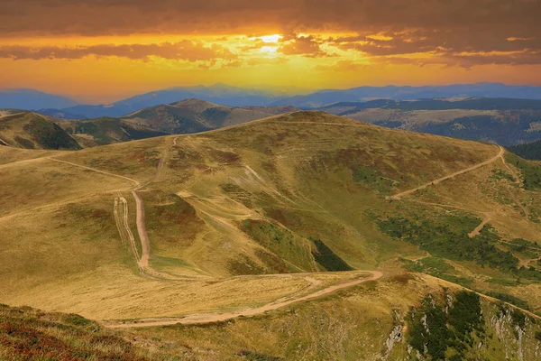 Sunset landscape win Carpathian mountains. Dirt road on mountain ridge top. Take it in Ukraine