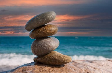 Günbatımı gökyüzü arka planında ıslak ballanlı deniz taşları