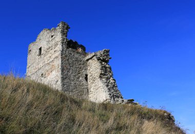 Tepedeki eski kulenin yıkıntısı mavi gökyüzü arka planına karşı