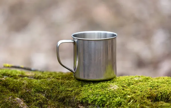 森林绿苔上的钢制旅游杯 图库图片