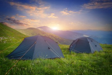 Dağlarda sabah çayırlarında iki turist çadırıyla manzara 