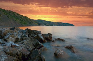 Deniz kıyısında taşlı güzel gün batımı manzarası