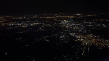 Yerin üstünde uçan uçaktan gece vakti şehrin parlak ışıklarının havadan çekilmiş görüntüsü.