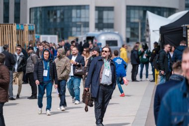 Moskova - 25 Mayıs 2022: Güneşli bir parkta düzenlenen iş konferansı sırasında pavyon yakınlarında yürüyen rozetli iş adamı kalabalığı