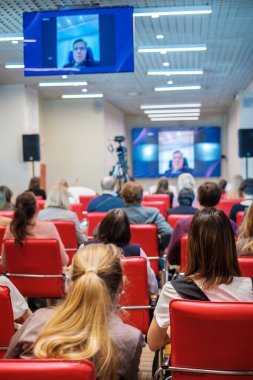 Dar oditoryumdaki iş seminerinde çevrimiçi konuşmacı dinleyen insanlar