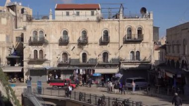 Ierusalim, İsrail - 12 Kasım 2022: İsrail 'in Eski Kudüs kentinin güneşli caddesinde eski binaların yakınına taşınan modern araçların ve binaların el kamerası