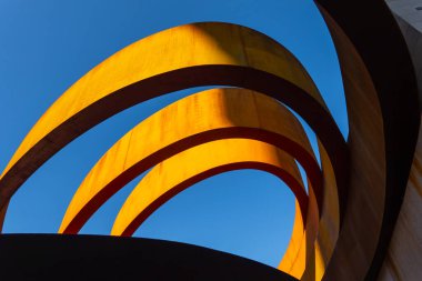 Çağdaş binanın dışından şehrin bulutsuz mavi gökyüzüne güneş ışığı yüzükleriyle çevrili.