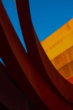 Günışığı turuncu duvarı ve bulutsuz mavi gökyüzünün altındaki çağdaş bina halkalarından.