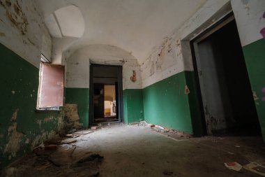 Gündüz vakti ıssız binanın içindeki yıpranmış duvarların kapısı ve penceresi açık güneşli koridor.