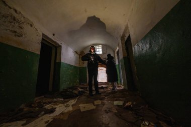 Dışardaki arkadaşlar el feneriyle terk edilmiş binanın eski karanlık koridorlarını geziyorlar.